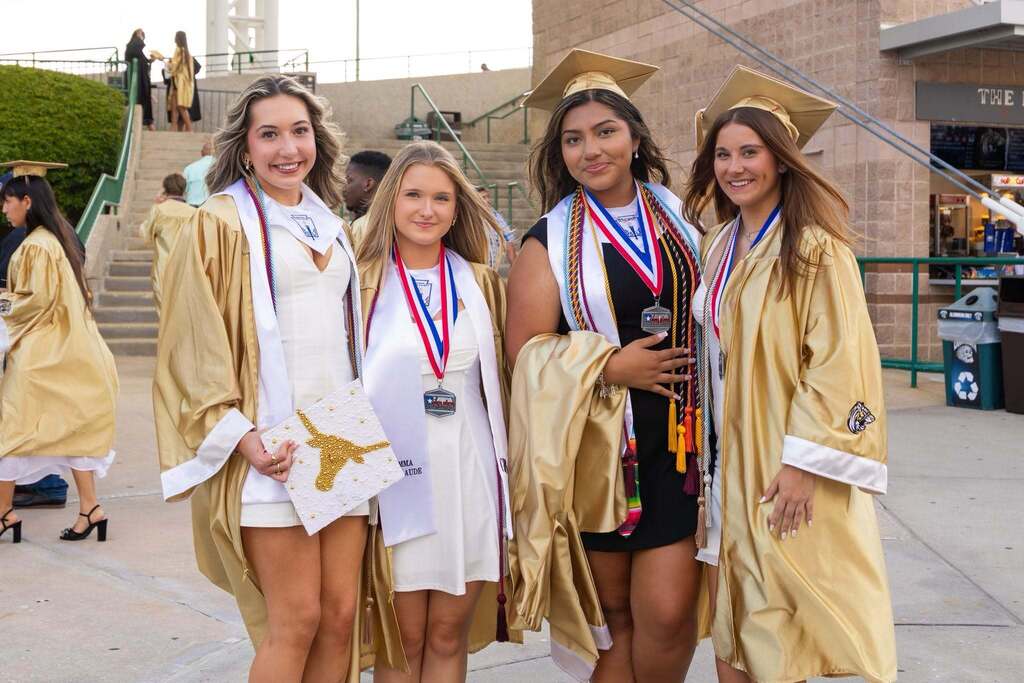 Four female students in gold caps and gowns.
