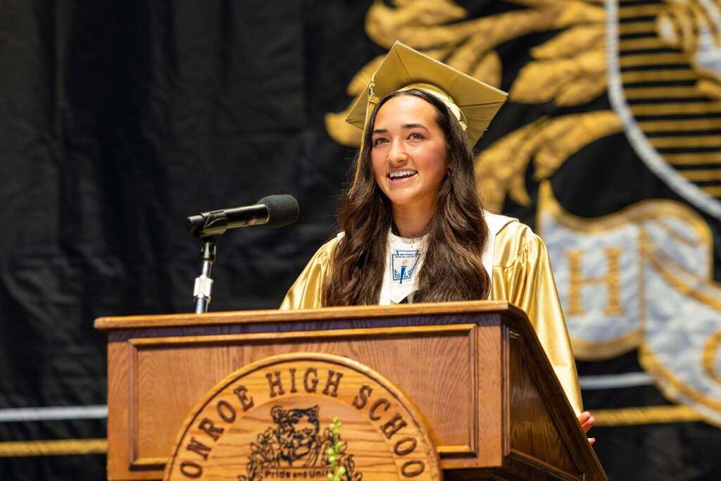 Female student give speech at graduation.
