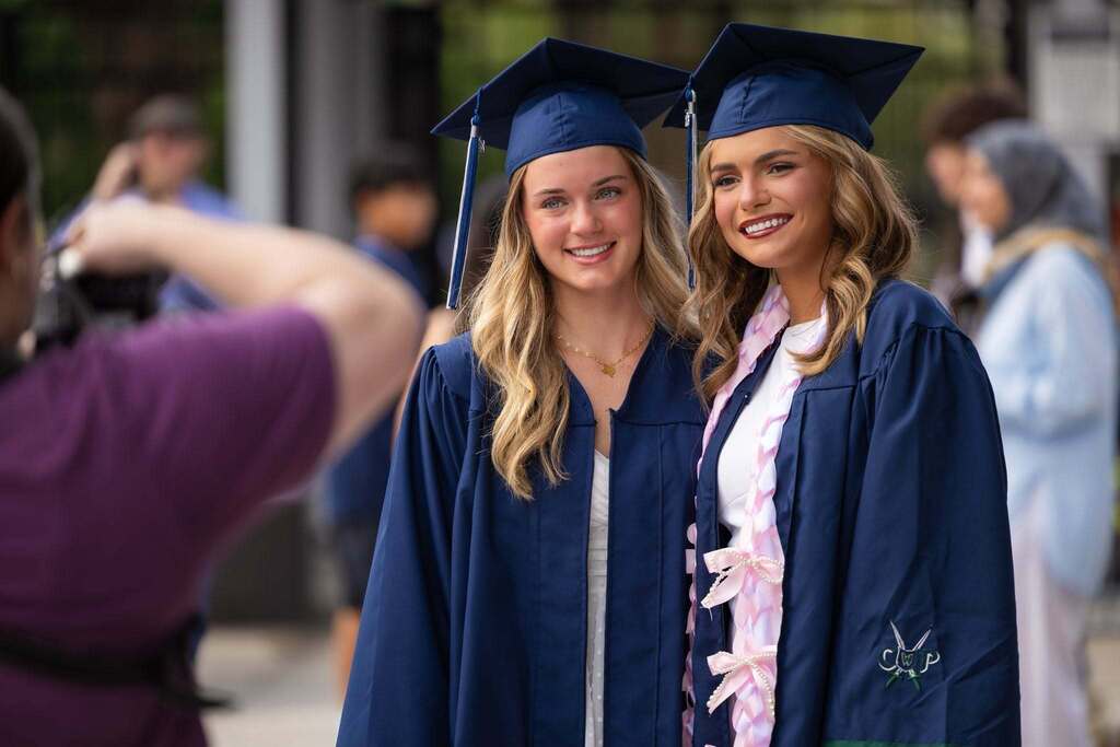 Two female graduates in dark blue robes.