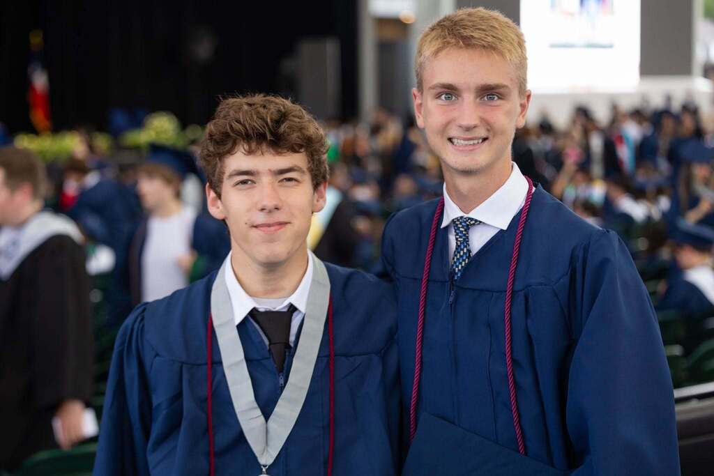 Two male graduates in dark blue robes.