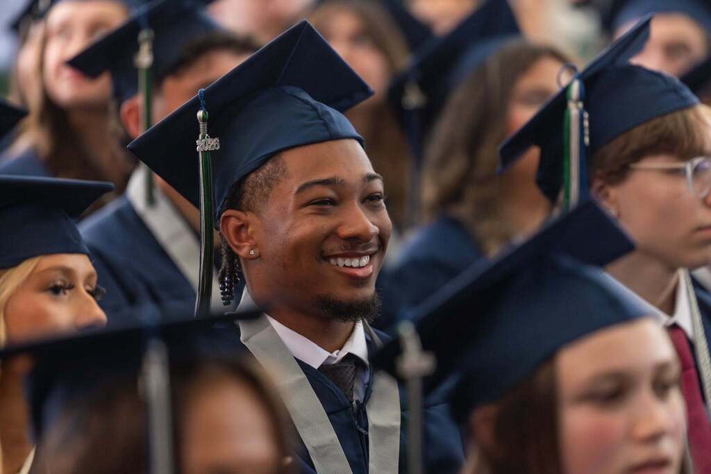 Male student in dark blue graduation cap smiling.