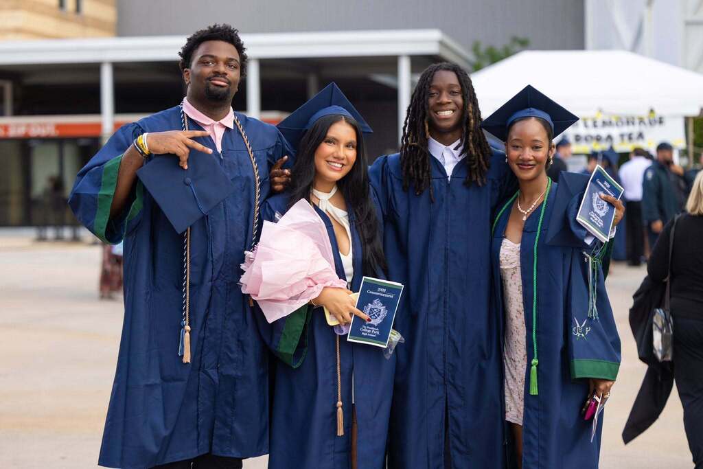 Two male and two female students in dark blue graduation gowns.