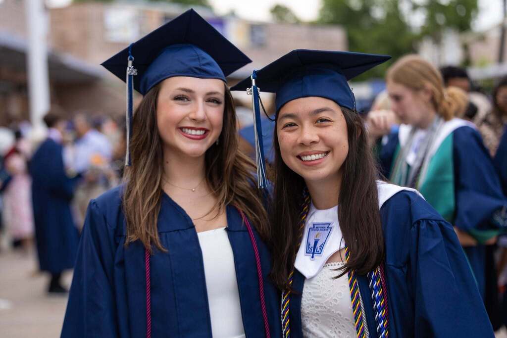 Two female graduates in dark blue caps and gowns.