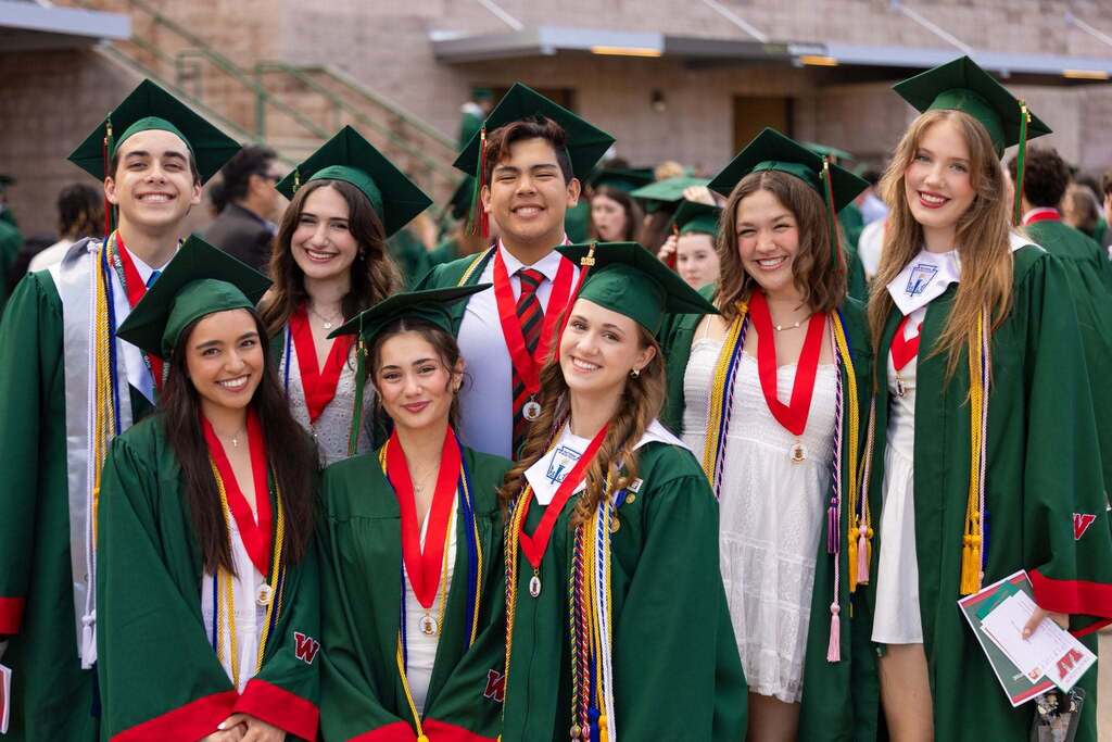 Several graduates in green caps and gowns.