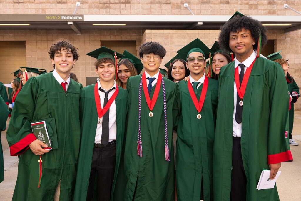 Several graduates in green caps and gowns.