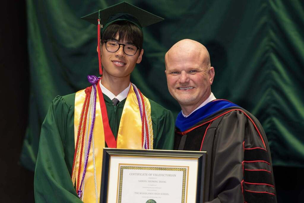 Valedictorian and Superintendent hold award plaque.