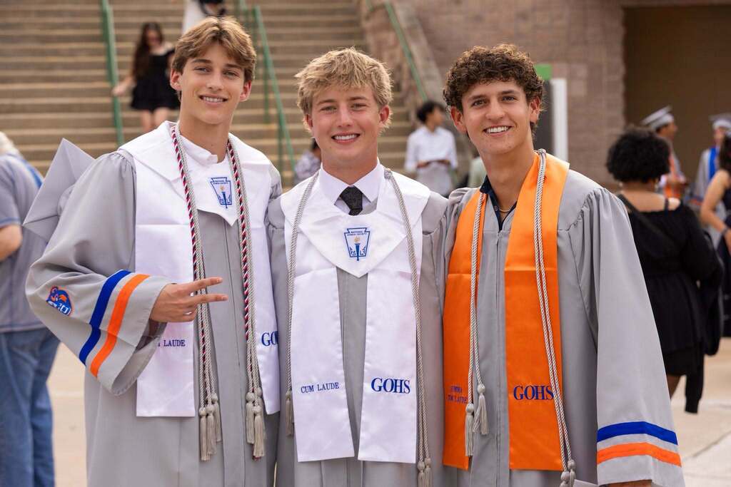 Three male graduates in gray caps and gowns.