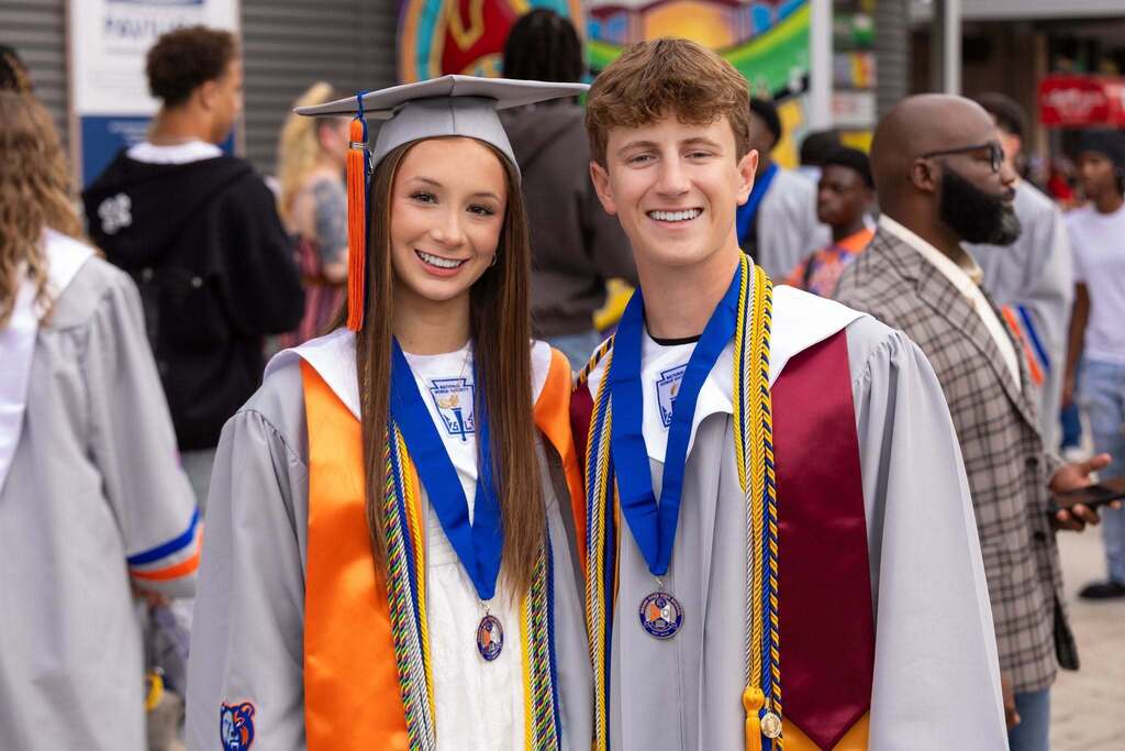 Male and female graduate in gray caps and gowns.
