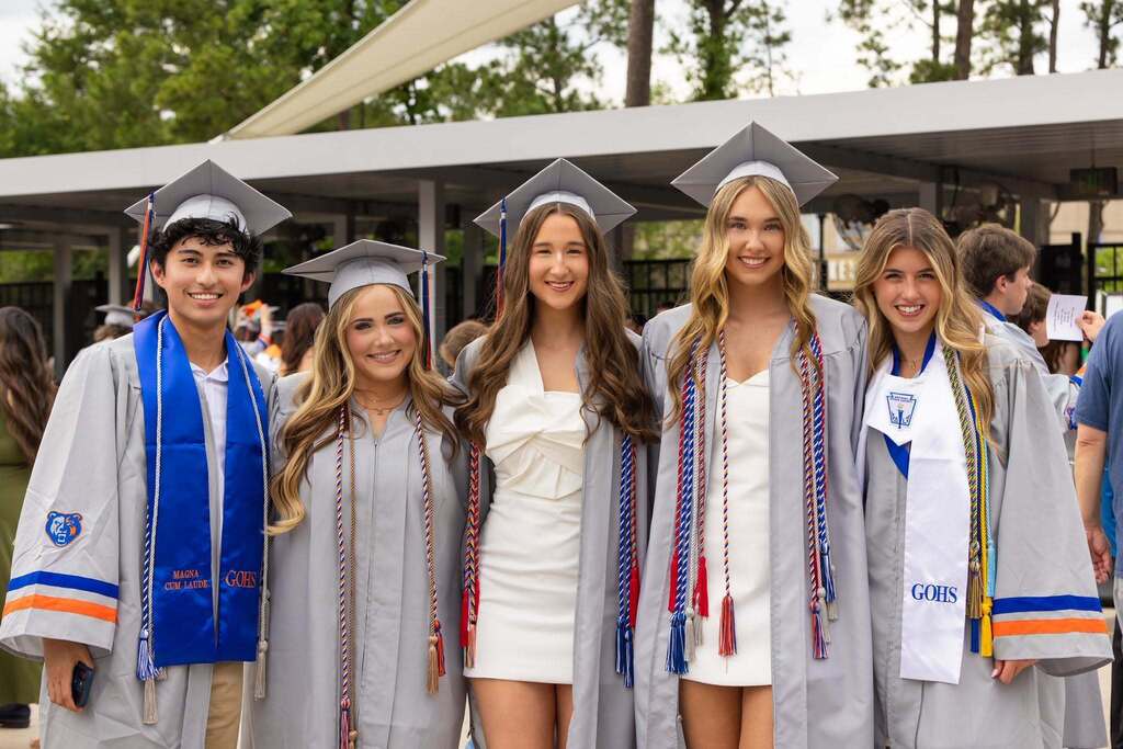 Five graduates in gray caps and gowns.