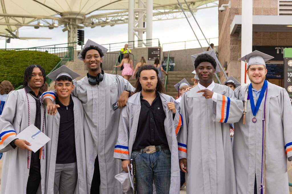 Six males graduates in gray caps and gowns.