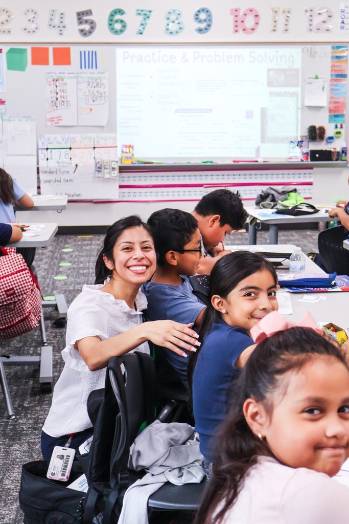 Teacher and students smiling together in the classroom.