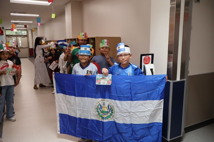 Students celebrate their cultural heritage while proudly displaying the El Salvador flag during a school parade.