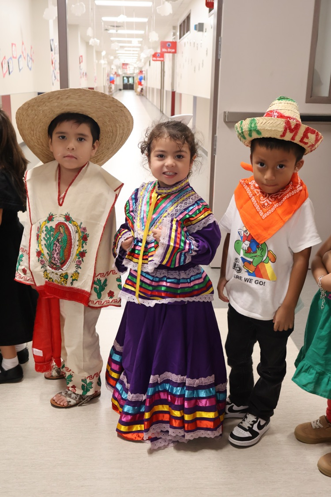 Three students celebrate Mexican culture in colorful traditional attire and sombreros during a school event.