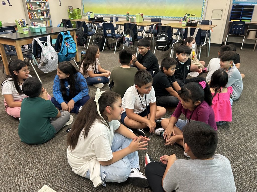 Several students seated on the floor in a classroom