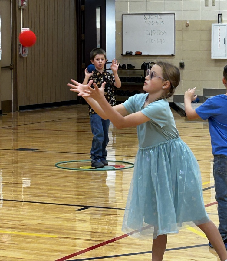 A student throwing a ball and another student catching a ball
