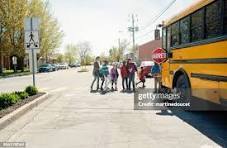 Bust stopped at crosswalk with students walking in crosswalk.