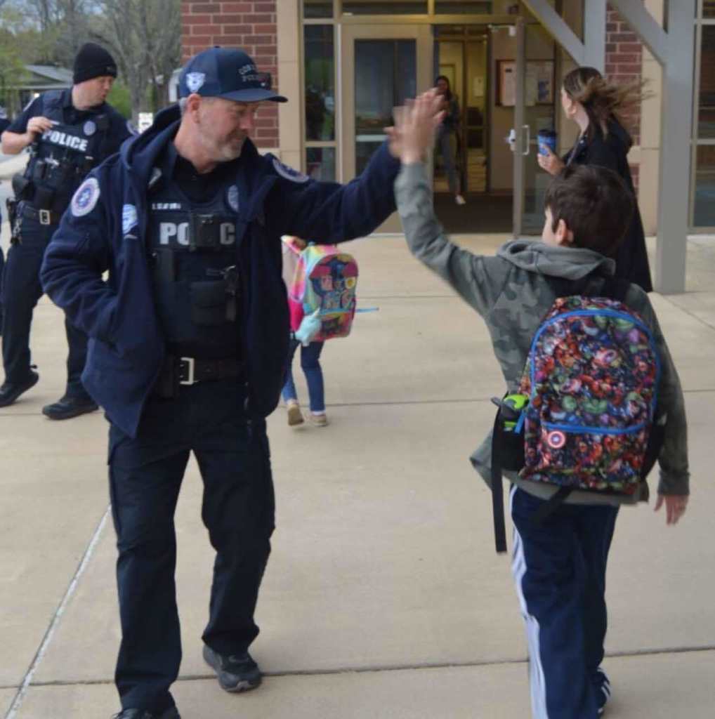 Officer Slayton high five-ing student