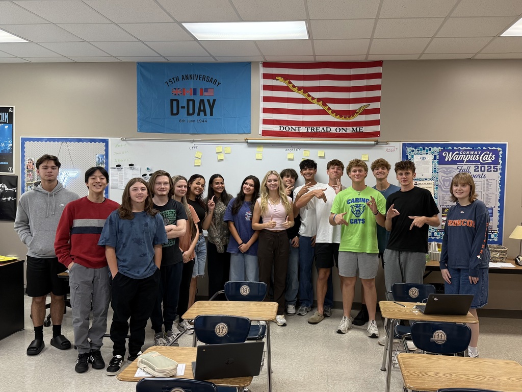 Class posing with their political ideology quiz results on the board behind them.