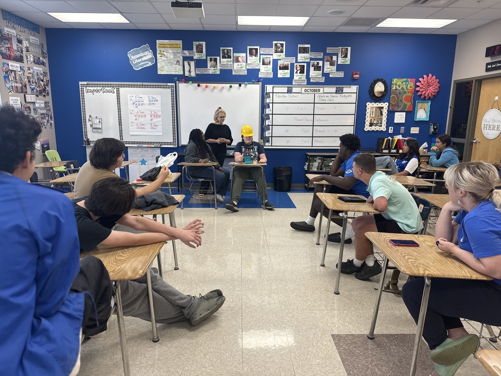 Students look on as a pair of students attempt to play the game "Taboo".