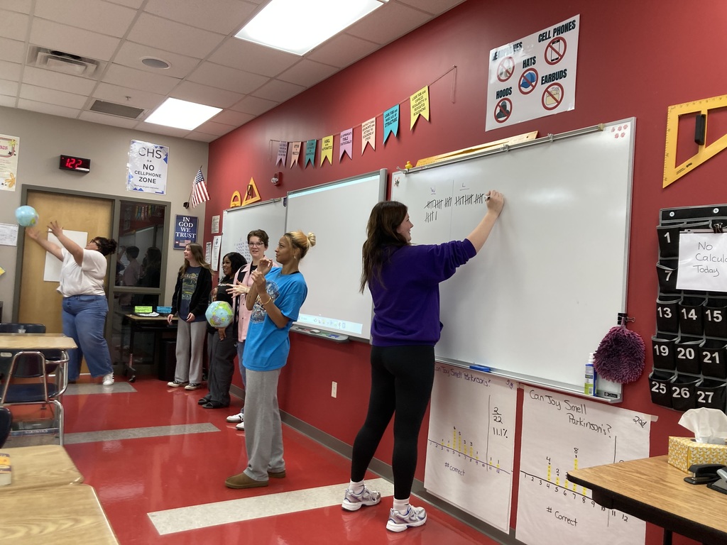 Students tossing inflatable globes to a partner. Another student keeps record of whether or not the recipient's fingers landed on water or land.