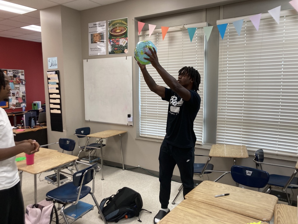 A student catches an inflatable globe in both hands.