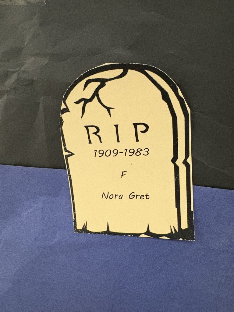 Paper tombstones on a paper graveyard. Students studying the data.