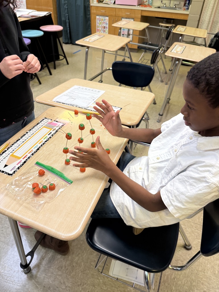 Students building pumpkin towers with candy pumpkins