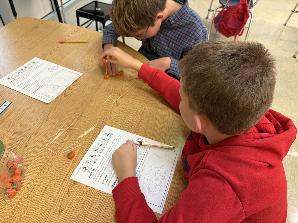 Students building pumpkin towers with candy pumpkins