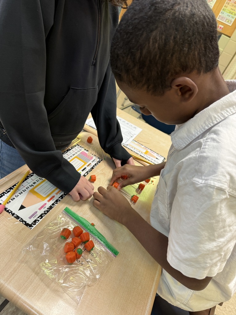 Students building pumpkin towers with candy pumpkins