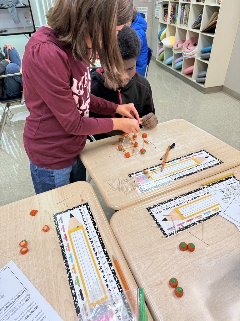 Students building pumpkin towers with candy pumpkins