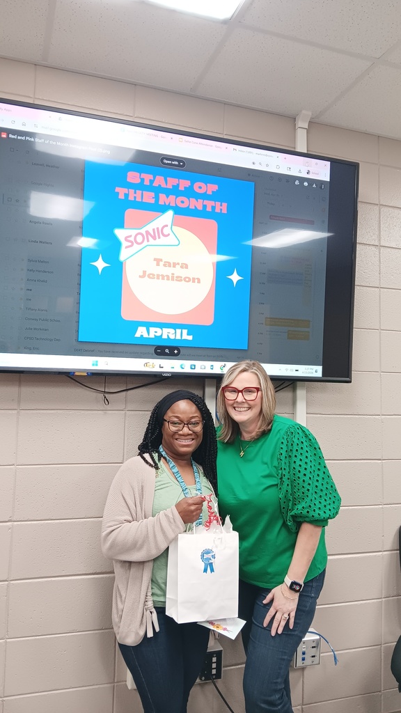 Two ladies standing with an award for staff of the month