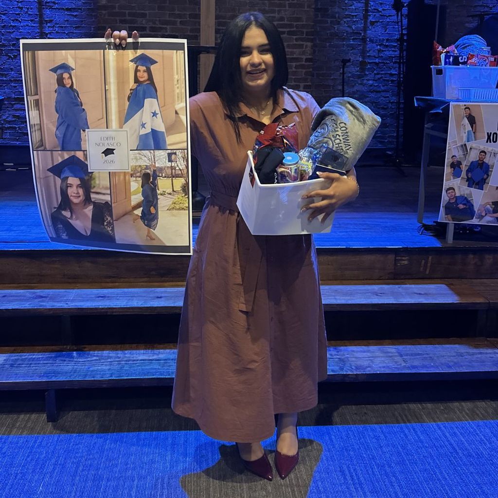 Student holding her grad poster and gift basket.