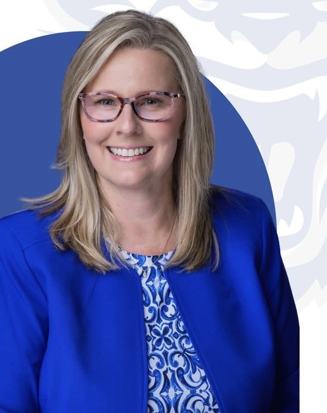 Principal smiling in blue outfit
