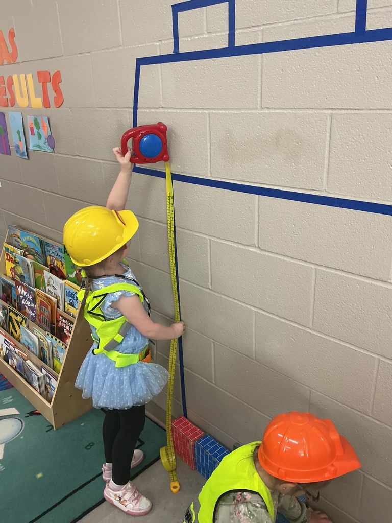 child measuring her house with a toy tape measure