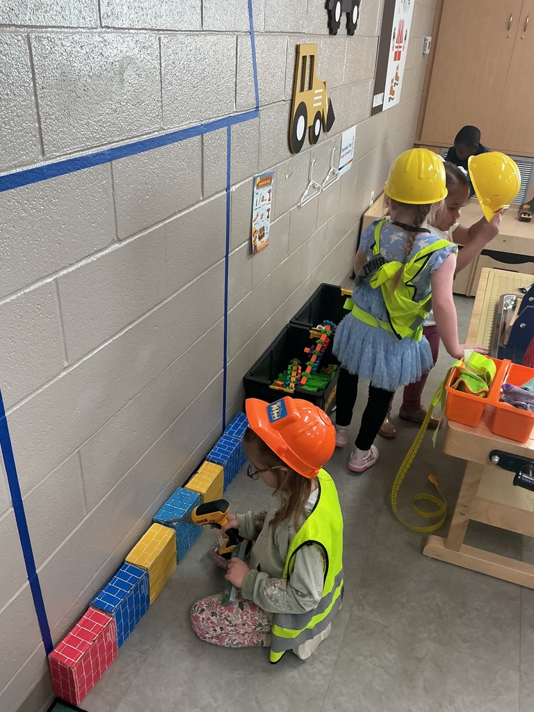 children wearing safety gear building their house using cardboard blocks