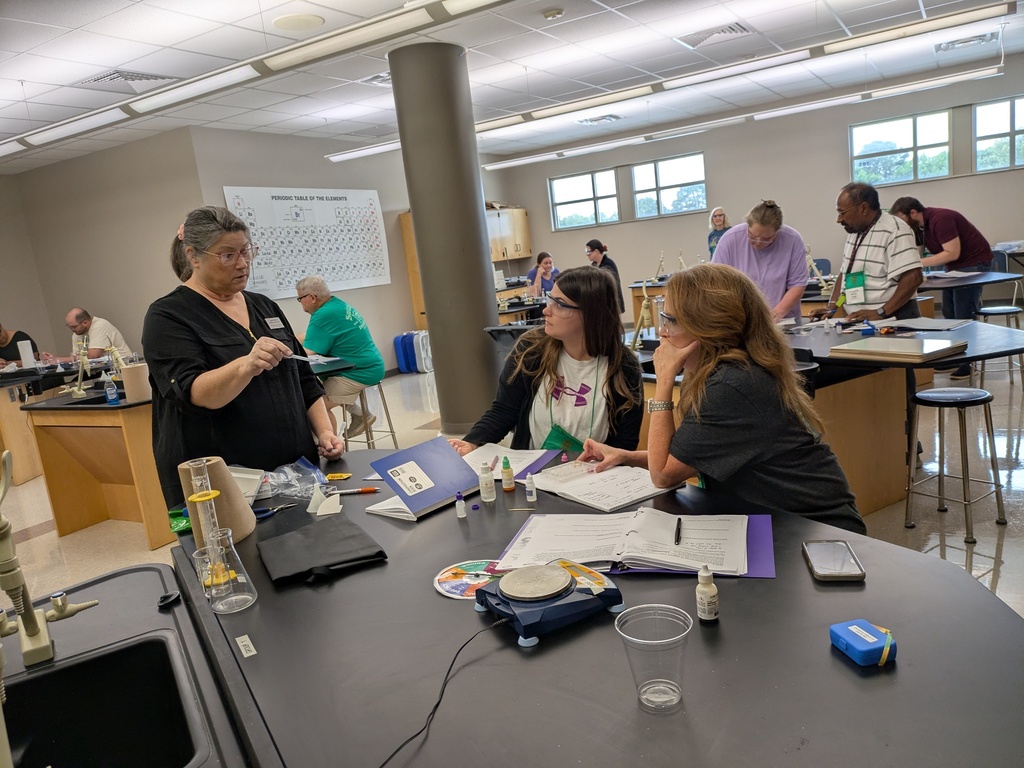 A pair of teachers at a lab table working through an activity and receiving guidance from the presenter.