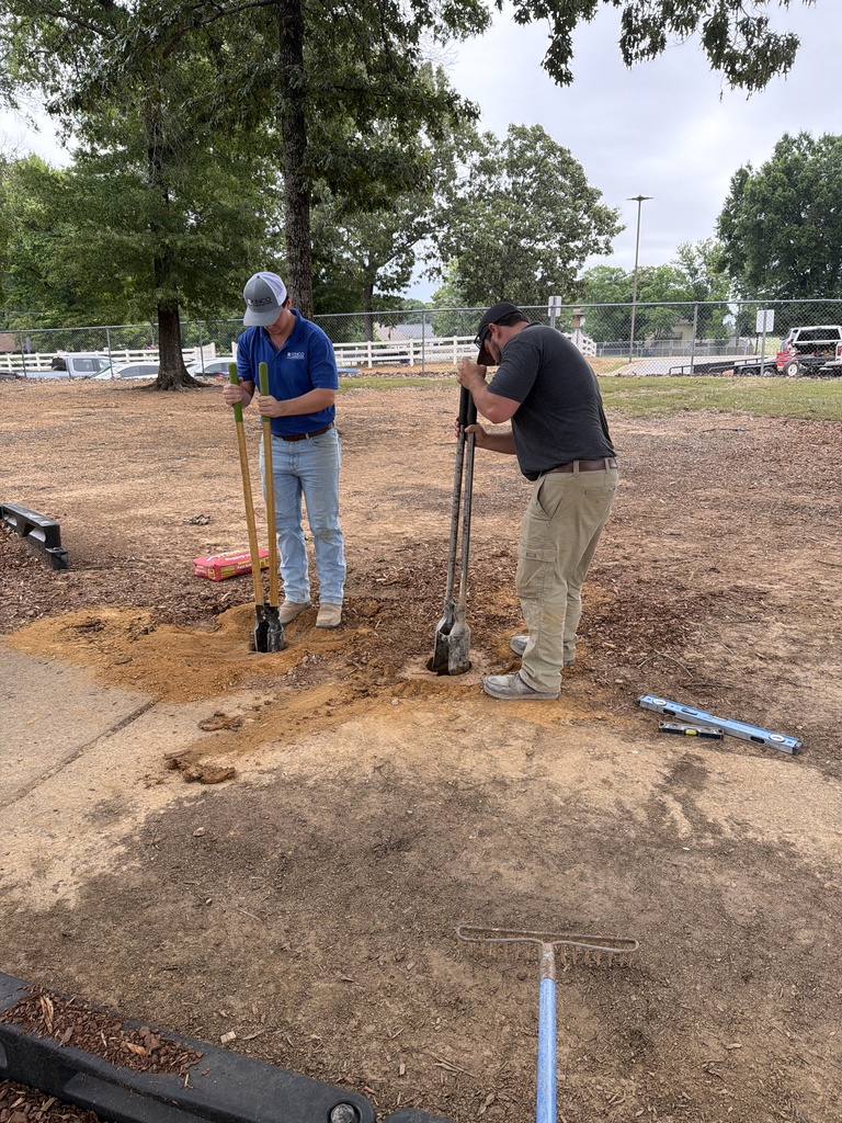Two men digging sign post holes on playgroune
