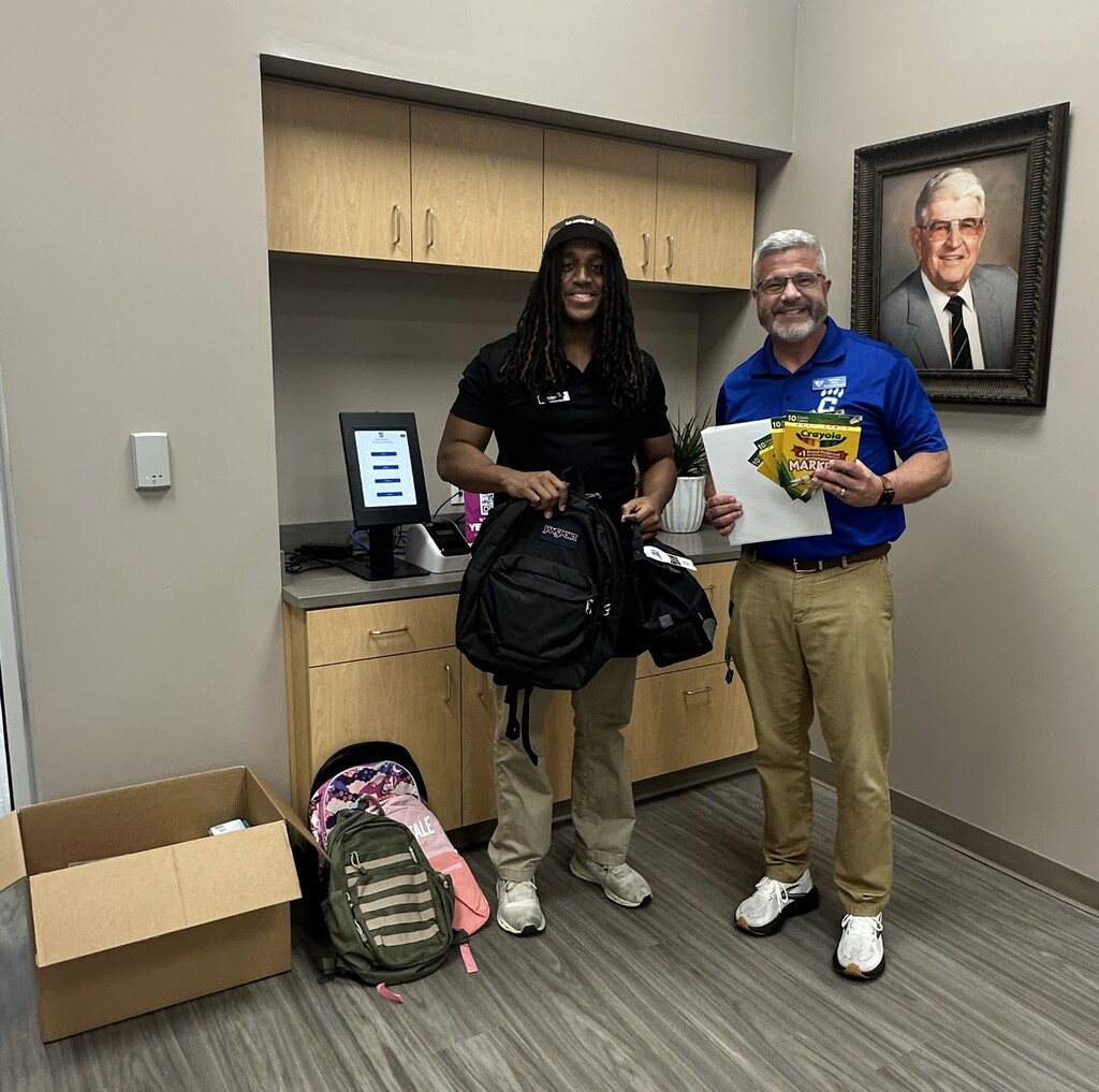 Eli from Planet Fitness and Mr. Etters holding up school supplies donated from their members at the recent school supply drive.
