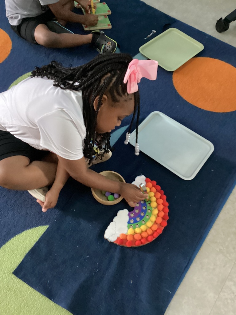 child using finer motor skills to put corresponding color of balls on the color of the rainbow