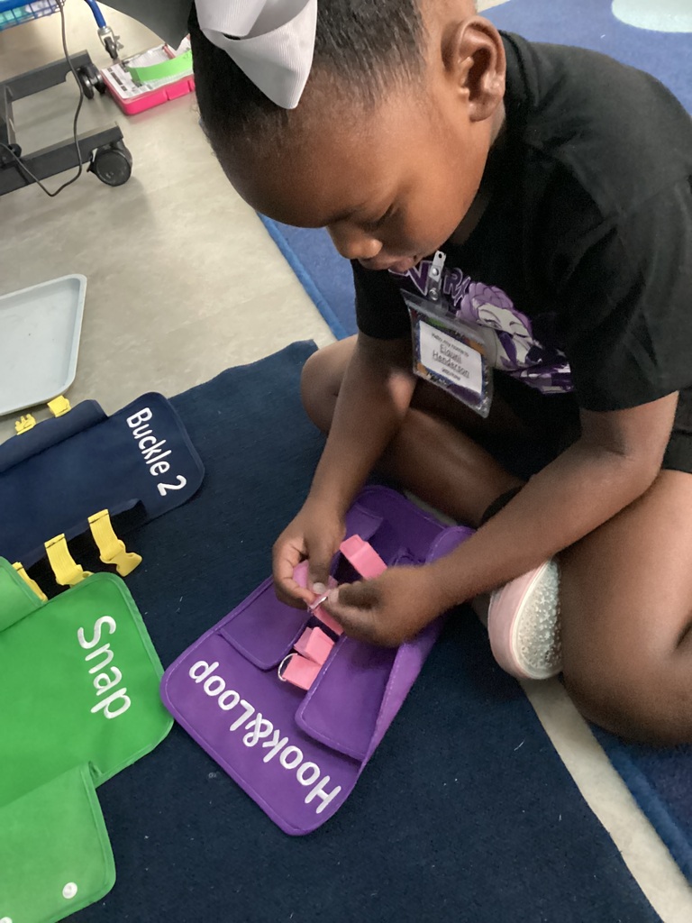child practicing life skills such as hooks and loops, snaps, and buckles 