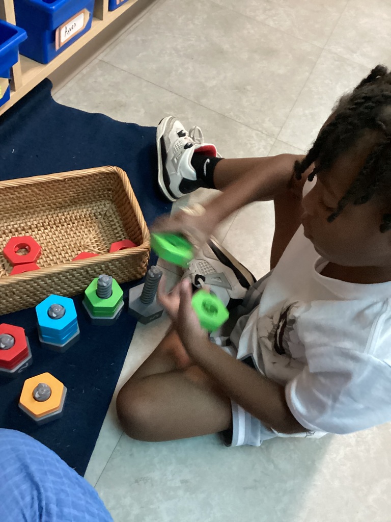 child using nuts and bolts to sort, count, and identify colors