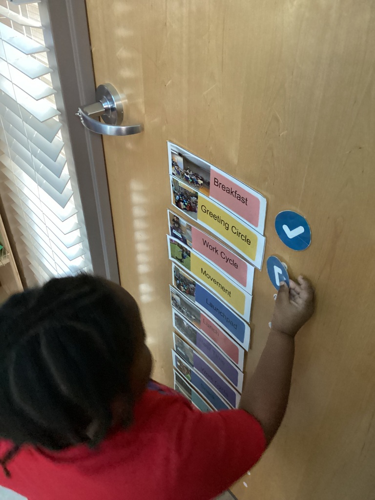 child putting check marks on the daily visual schedule to signify the next activity for the day