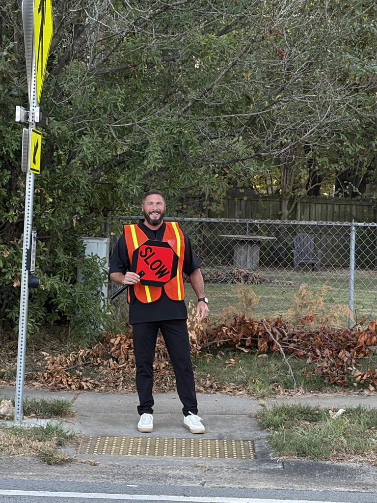 Mr. Black helping kids cross the street holding sign