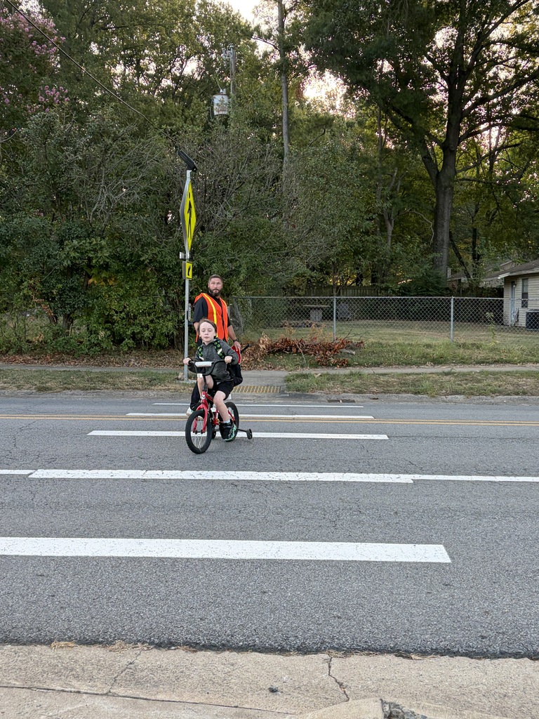 Mr. Black helping kids cross the street holding sign