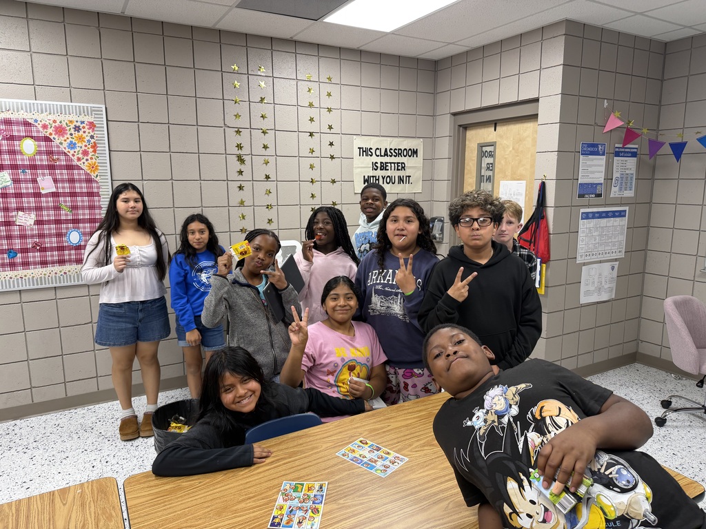 Eleven students putting up peace signs and smiling.