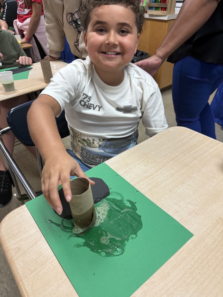 Student smiling and working on his bubbly “potion” for his witch’s cauldron potion art