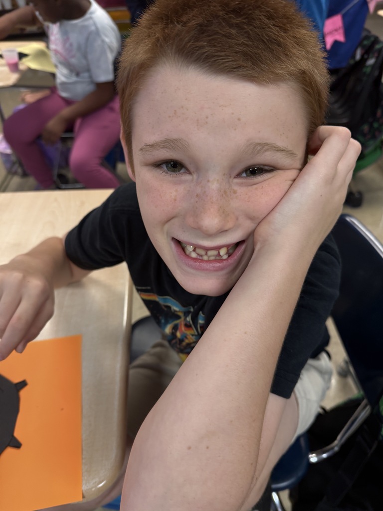 Student smiling and posing next to his bubbly “potion” for his witch’s cauldron potion art