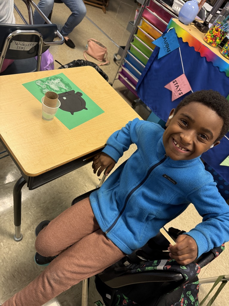 Student smiling and posing next to his bubbly “potion” for his witch’s cauldron potion art
