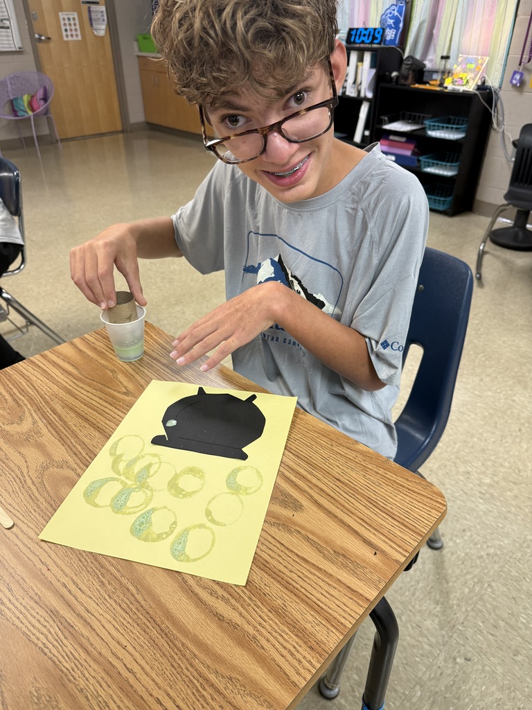 Student smiling and posing next to his bubbly “potion” for his witch’s cauldron potion art