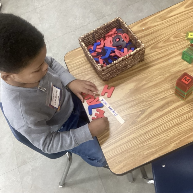 child building his name using letters and a copy of his name 
